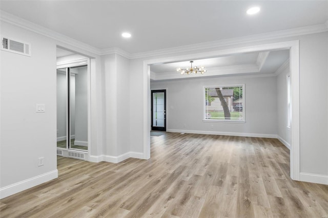 empty room featuring light hardwood / wood-style flooring, an inviting chandelier, and ornamental molding