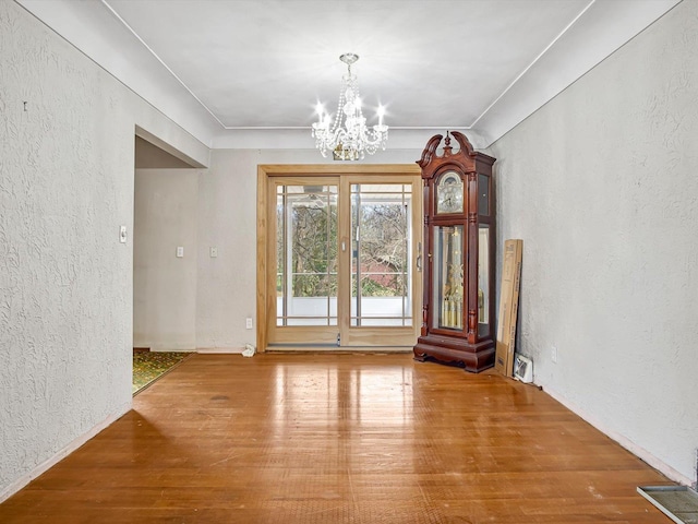 unfurnished dining area with hardwood / wood-style floors and a chandelier