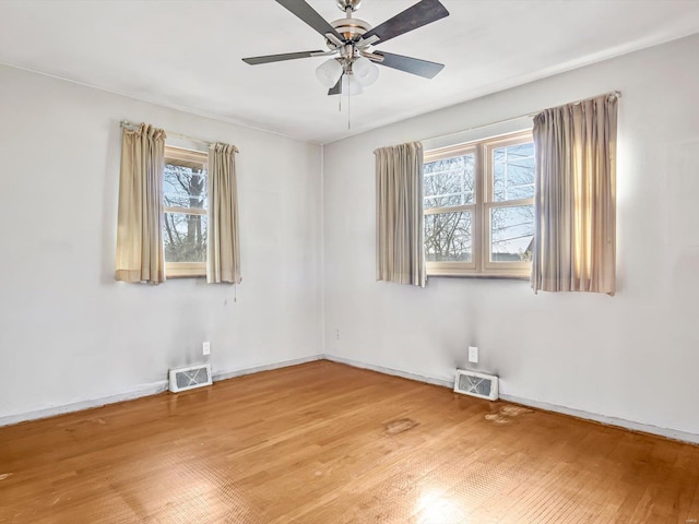 empty room with ceiling fan, plenty of natural light, and hardwood / wood-style flooring