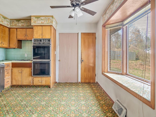 kitchen with double oven, ceiling fan, tasteful backsplash, and a healthy amount of sunlight