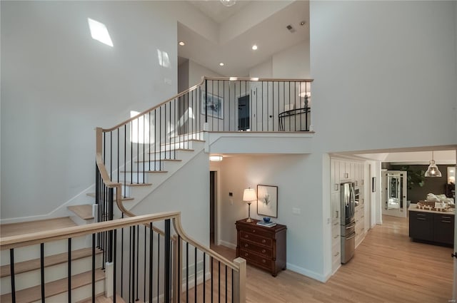 staircase with a high ceiling and hardwood / wood-style flooring