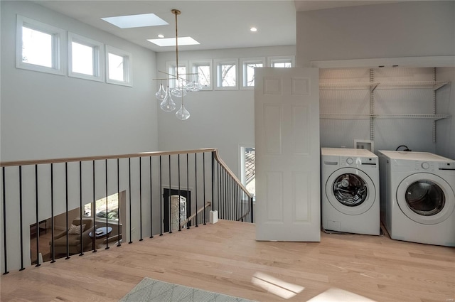 laundry room featuring a skylight, a healthy amount of sunlight, washer and dryer, and hardwood / wood-style flooring