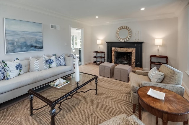 living room with light wood-type flooring, crown molding, and a premium fireplace