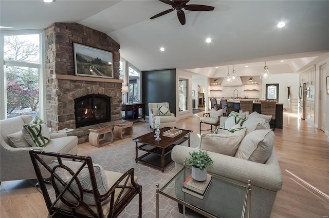 living room featuring a fireplace, light hardwood / wood-style flooring, a healthy amount of sunlight, and vaulted ceiling