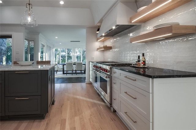 kitchen with white cabinets, wall chimney exhaust hood, a healthy amount of sunlight, and double oven range