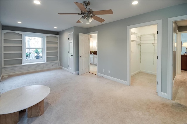 unfurnished room with ceiling fan, light colored carpet, and built in shelves