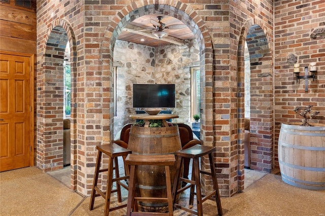 bar with light carpet, brick wall, a wealth of natural light, and ceiling fan