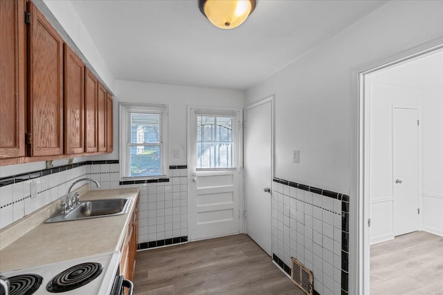 kitchen featuring light wood-type flooring, white range, tile walls, and sink