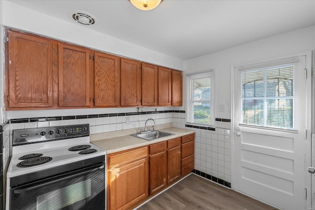 kitchen featuring dark hardwood / wood-style flooring, white range with electric stovetop, tile walls, and sink