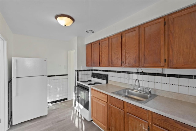 kitchen featuring backsplash, white appliances, sink, and light hardwood / wood-style flooring