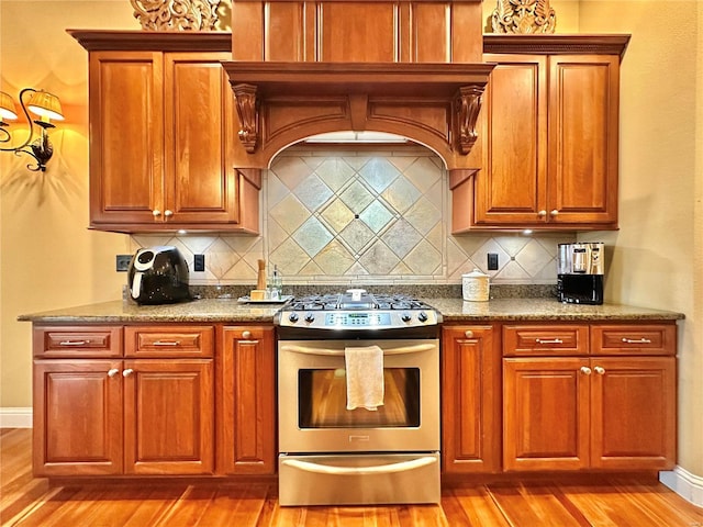 kitchen with decorative backsplash, light wood-type flooring, and stainless steel range with gas stovetop