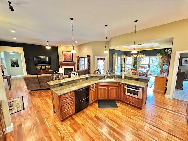 kitchen featuring light stone countertops, sink, dishwasher, and decorative light fixtures