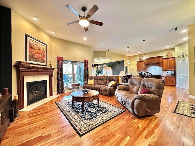 living room featuring ceiling fan with notable chandelier and light hardwood / wood-style floors