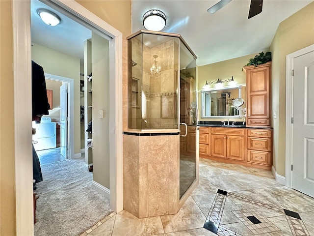 bathroom featuring vanity, ceiling fan with notable chandelier, tile patterned flooring, a shower with shower door, and washer / clothes dryer