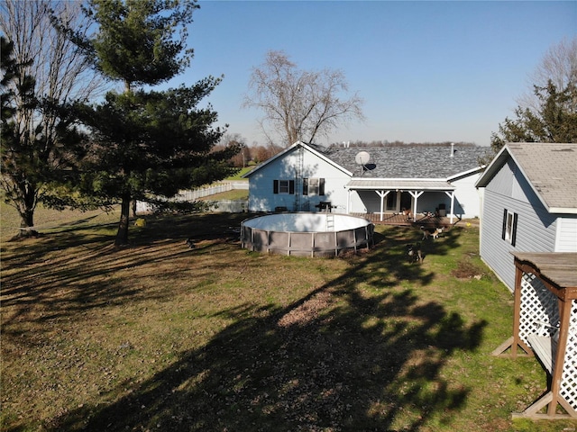 back of property with an outdoor pool and a yard