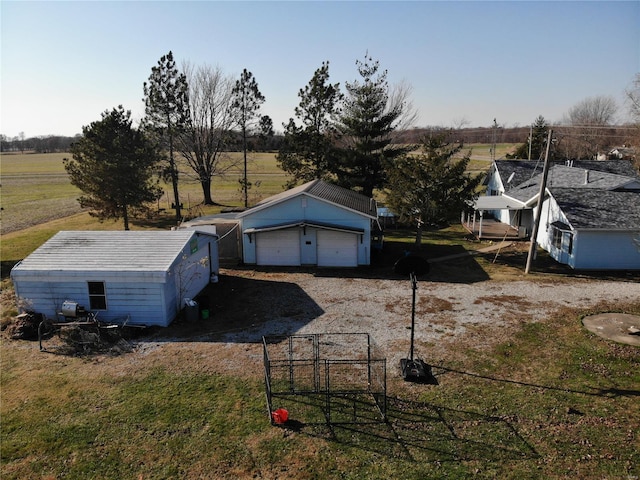 view of yard featuring a garage, a rural view, and an outdoor structure