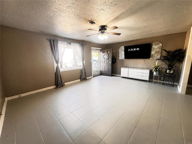 unfurnished living room with ceiling fan, tile patterned flooring, visible vents, and baseboards