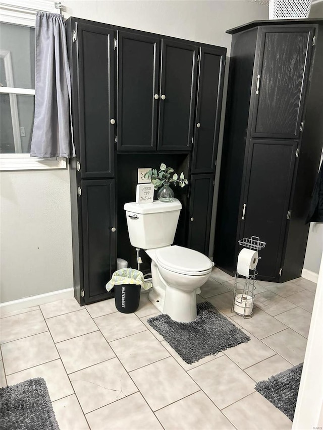 bathroom with tile patterned flooring, baseboards, and toilet