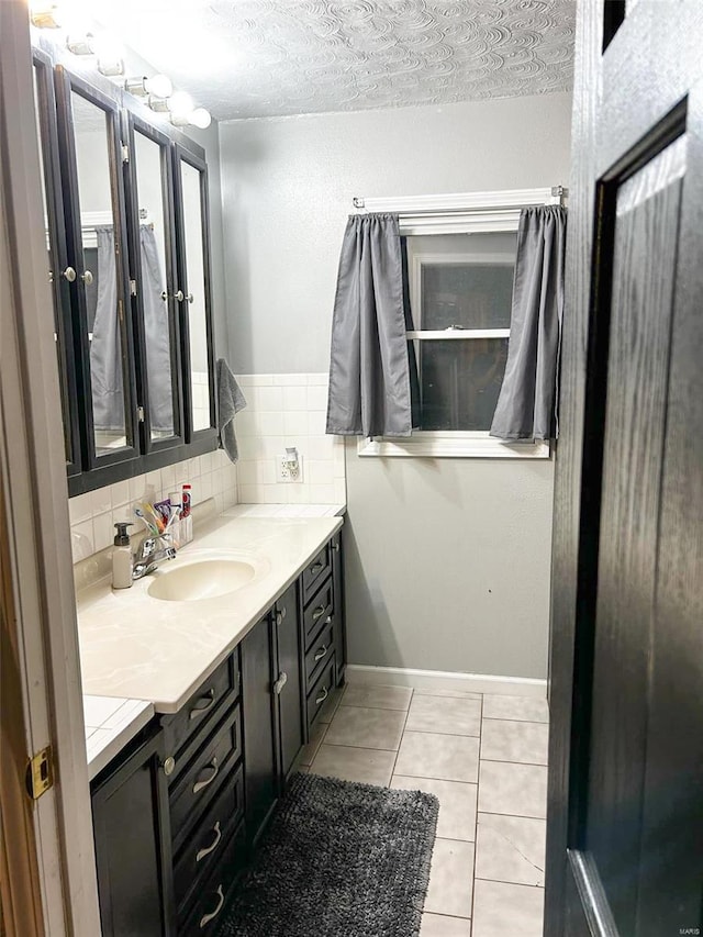 bathroom featuring backsplash, a textured ceiling, vanity, tile patterned flooring, and baseboards