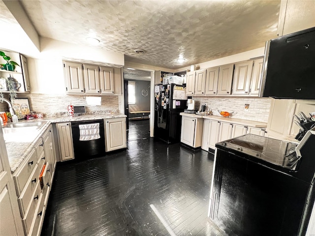 kitchen featuring dark wood-style floors, a sink, light countertops, black appliances, and backsplash