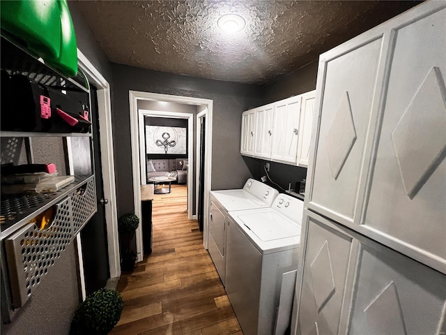 laundry area featuring cabinet space, washing machine and dryer, a textured ceiling, and dark wood-style flooring