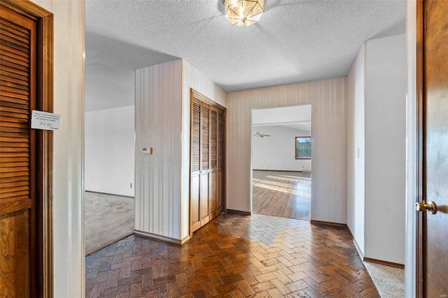 hall with dark parquet flooring and a textured ceiling