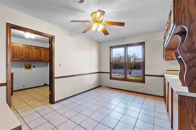 unfurnished room featuring ceiling fan, light tile patterned floors, and a textured ceiling