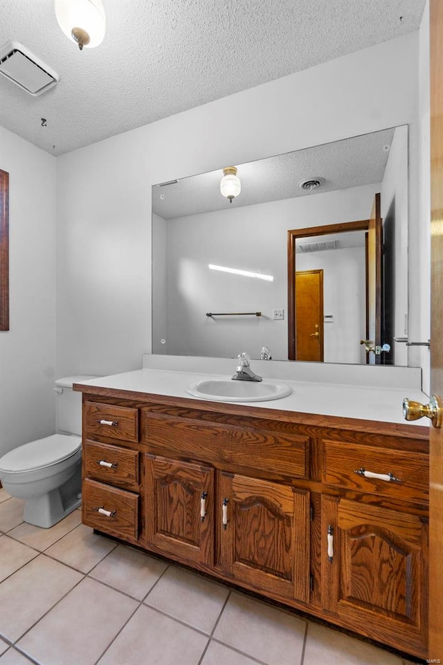 bathroom featuring tile patterned flooring, vanity, a textured ceiling, and toilet