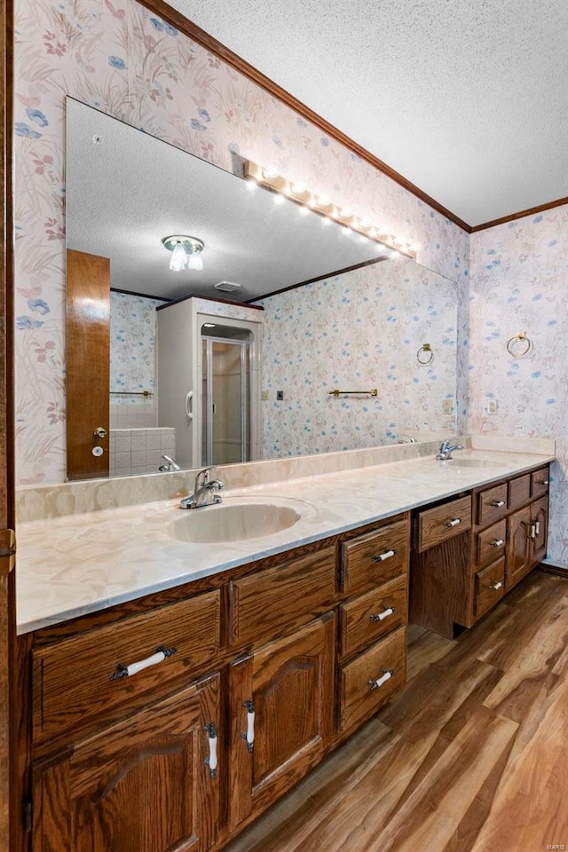 bathroom featuring crown molding, vanity, wood-type flooring, and a textured ceiling