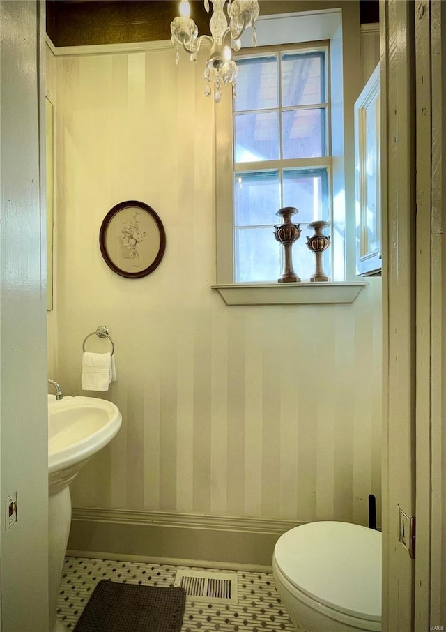 bathroom with tile patterned floors, a notable chandelier, and toilet