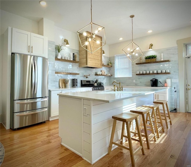 kitchen with a kitchen bar, appliances with stainless steel finishes, backsplash, light hardwood / wood-style flooring, and white cabinets