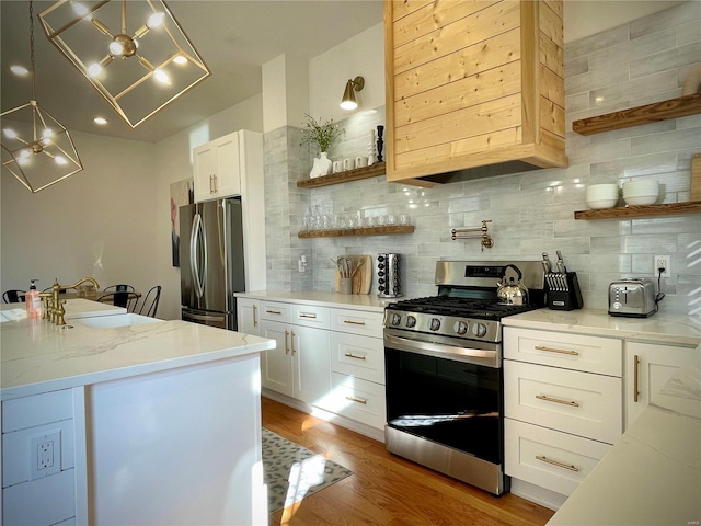 kitchen with light wood-type flooring, white cabinetry, light stone counters, and appliances with stainless steel finishes