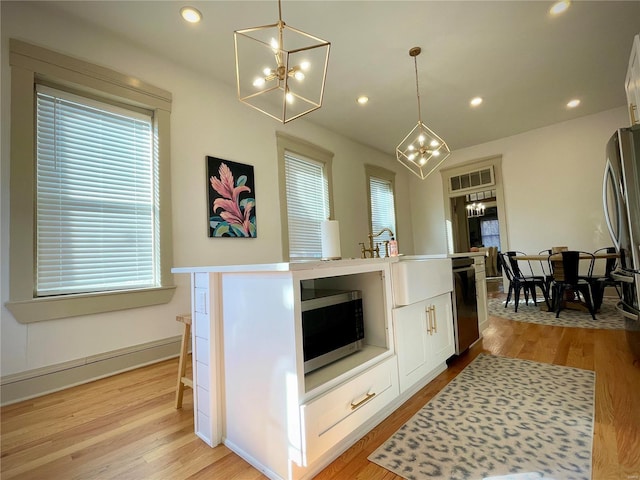 kitchen with appliances with stainless steel finishes, a center island with sink, and light hardwood / wood-style flooring