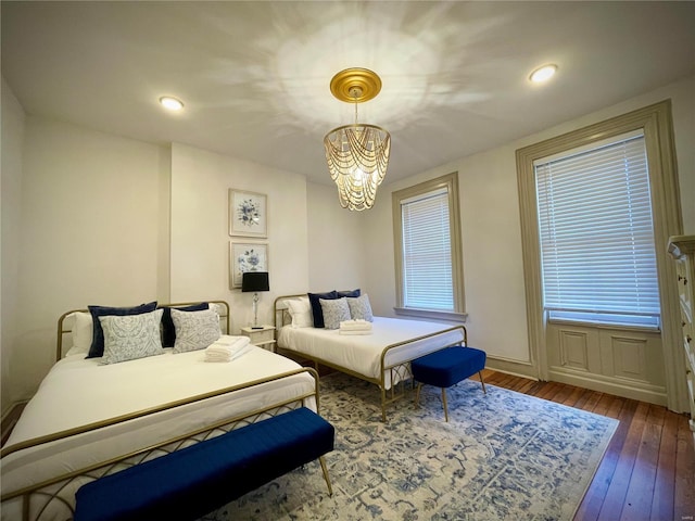 bedroom with dark hardwood / wood-style flooring and an inviting chandelier