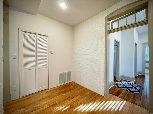 hall featuring light hardwood / wood-style floors and brick wall