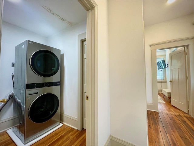 laundry area with hardwood / wood-style floors and stacked washing maching and dryer