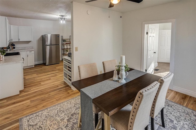 dining room featuring a textured ceiling, light hardwood / wood-style flooring, and ceiling fan