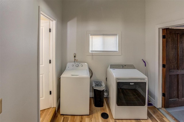 laundry area with washing machine and dryer and light wood-type flooring