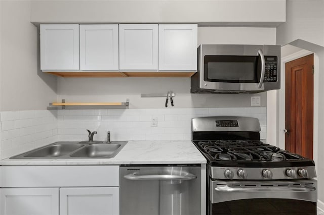 kitchen with white cabinets, appliances with stainless steel finishes, tasteful backsplash, and sink