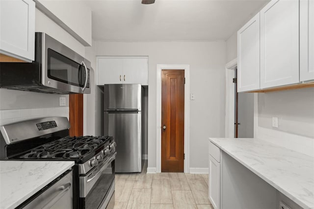 kitchen with white cabinets, appliances with stainless steel finishes, and light stone countertops