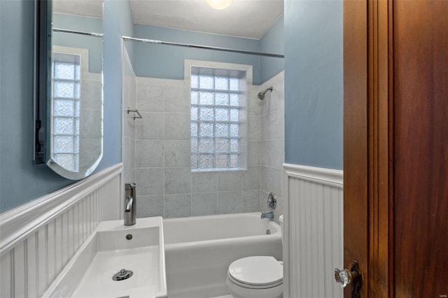 bathroom with toilet and tiled shower / bath