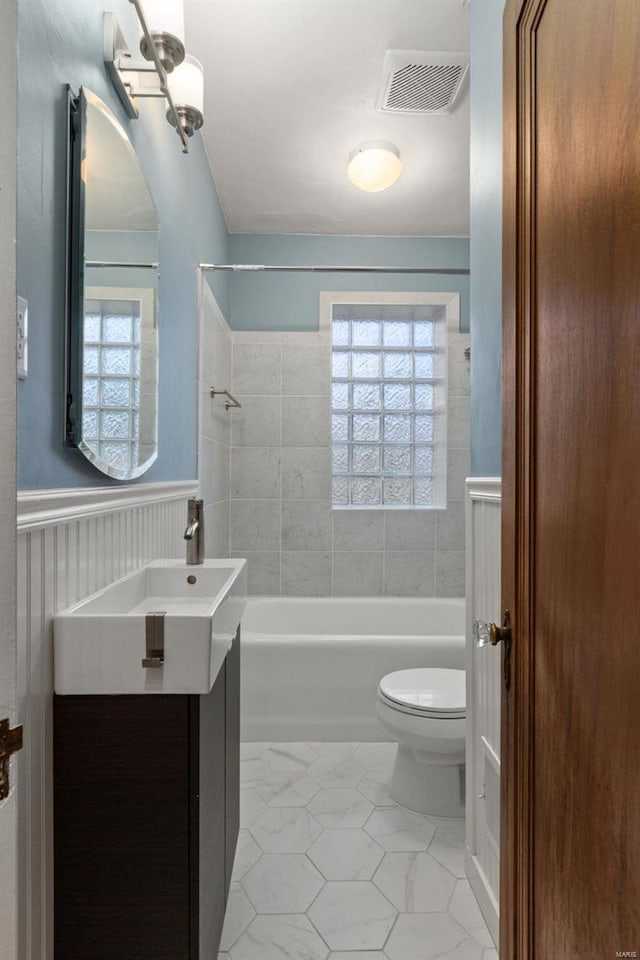 full bathroom with tiled shower / bath, vanity, and toilet