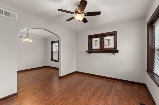 spare room with dark hardwood / wood-style floors, crown molding, and ceiling fan with notable chandelier