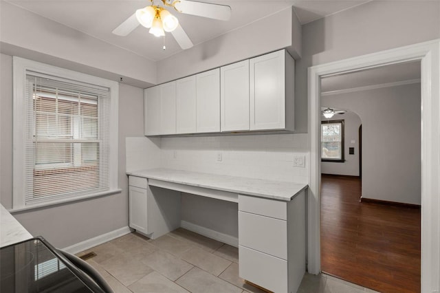 unfurnished office featuring built in desk, a wealth of natural light, and ceiling fan