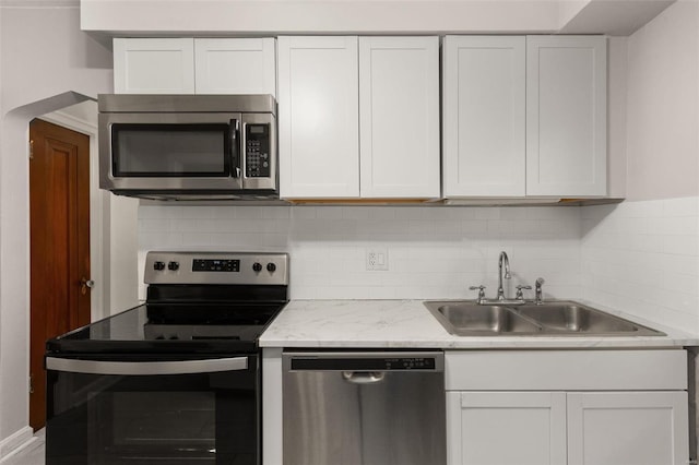 kitchen featuring white cabinets, sink, decorative backsplash, light stone countertops, and appliances with stainless steel finishes