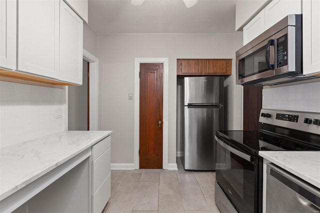 kitchen featuring white cabinets, light stone counters, stainless steel appliances, and tasteful backsplash