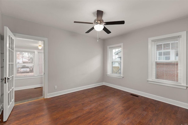 empty room with dark wood-type flooring, ceiling fan, and a healthy amount of sunlight