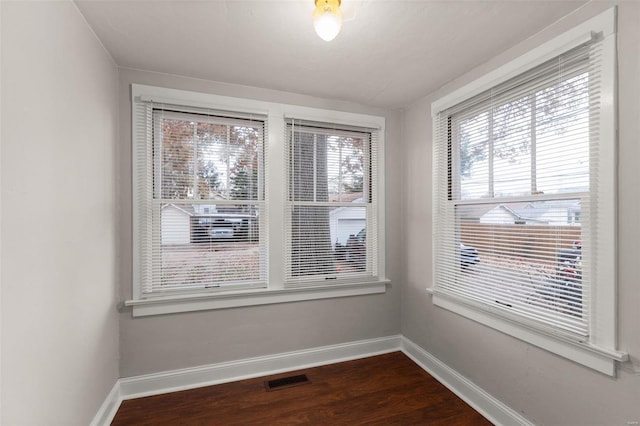 empty room featuring dark hardwood / wood-style flooring and a wealth of natural light