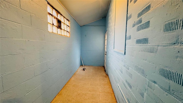 corridor featuring light tile patterned flooring and vaulted ceiling