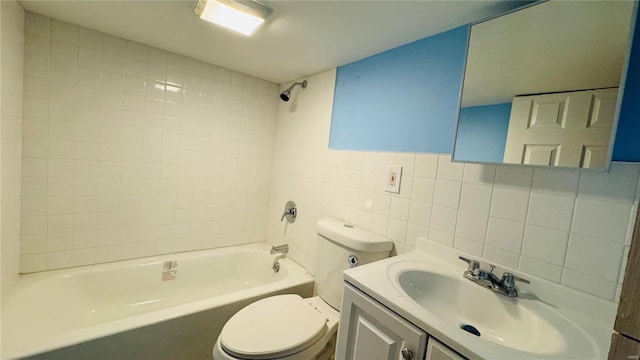 full bathroom featuring tile walls, vanity, tiled shower / bath combo, and toilet